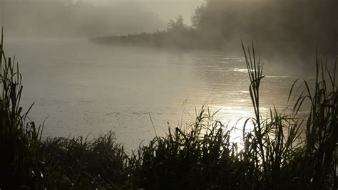 Early Morning Sunrise Reflections In Misty Fog On Flowing River Water