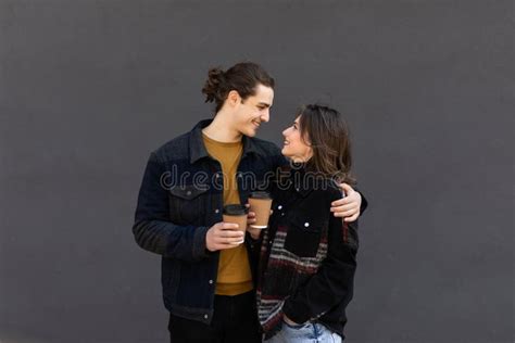 Boyfriend And Girlfriend With Disposable Cups Of Coffee Hugging In City