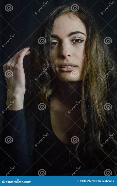portrait of a beautiful italian girl with long hair with her hand next to her face and with a