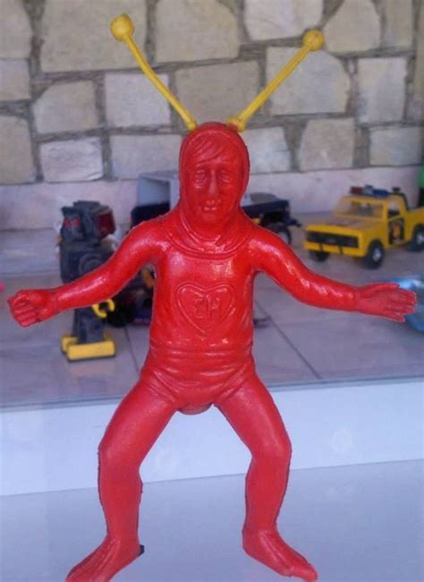 A Red Plastic Figure With Two Yellow Sticks In Its Head And Arms
