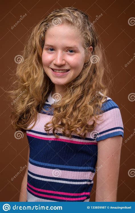 Young Beautiful Blonde Teenage Girl Smiling Against Brown Background Stock Image - Image of ...