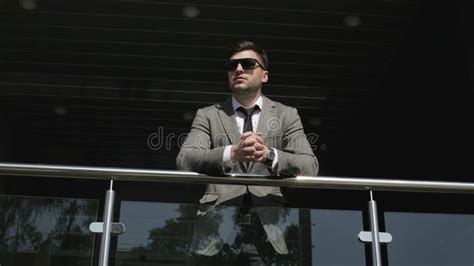 A Businessman Â Is Leaning Against The Railing At The Entrance To The Business Center Stock