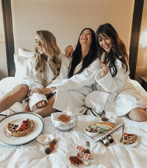 three women in robes sitting on a bed with breakfast foods and waffles around them