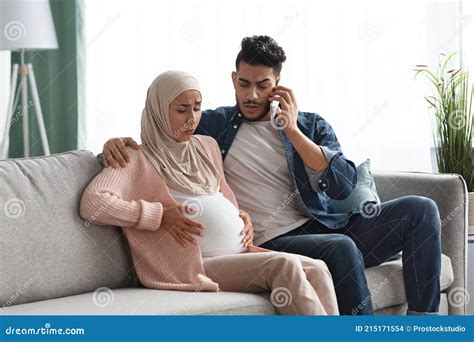 Pregnant Muslim Woman Suffering Labor Pain At Home Her Husband Calling Doctor Royalty Free