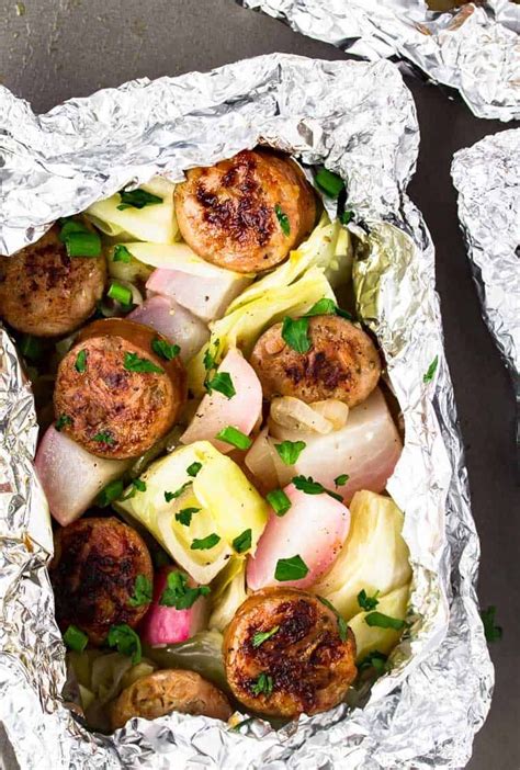 Turn your campfire—or even your grill!—into a working stove. Sausage and cabbage foil packets with radishes close up on ...