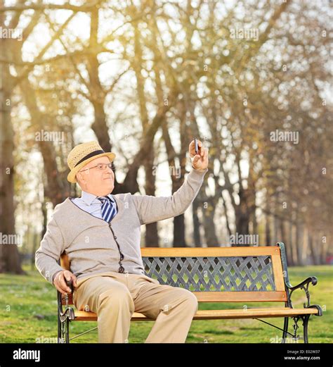 Senior Adult Taking A Selfie In Park Seated On Bench Stock Photo Alamy