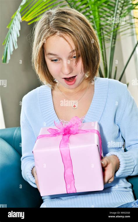 Surprised Teenage Girl Holding Wrapped Present And Smiling Stock Photo