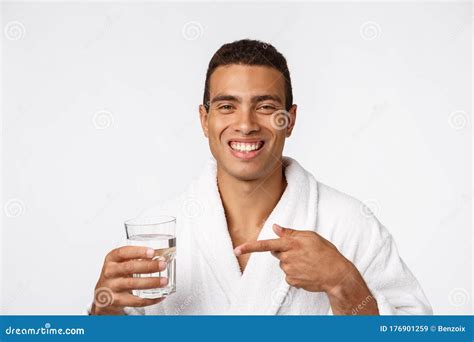 An Attractive Man Drinking A Glass Of Water Against White Background