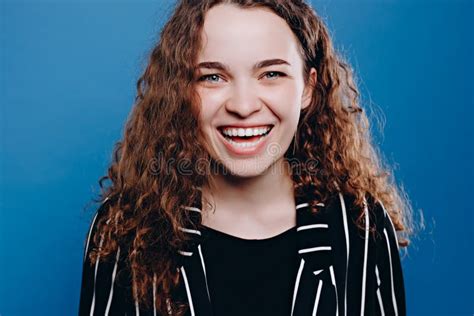 Portrait Of Beautiful Cheerful Girl With Curly Hair Smiling Laughing Looking At Camera Over Blue