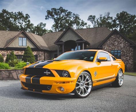An Orange Mustang Parked In Front Of A House