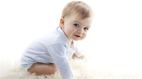 Cute Smiley Baby Boy Is Sitting Down On White Woolen Floor Carpet
