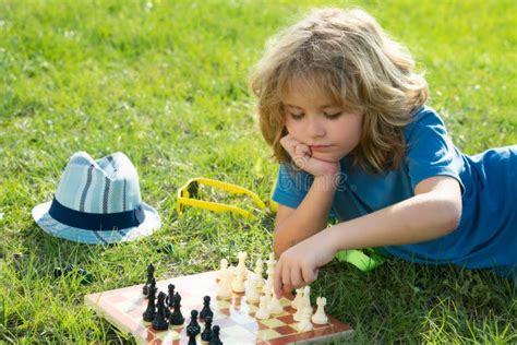 Child Playing Chess Game In Spring Backyard Laying On Grass