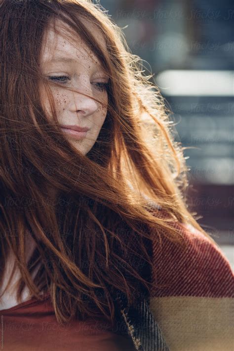 A Girl With Ginger Hair Gently Smiling As The Wind Catches Her Hair