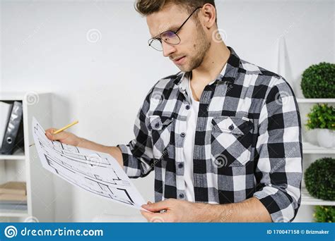Young Adult Architect Working With Blueprints In Workplace Studio Stock
