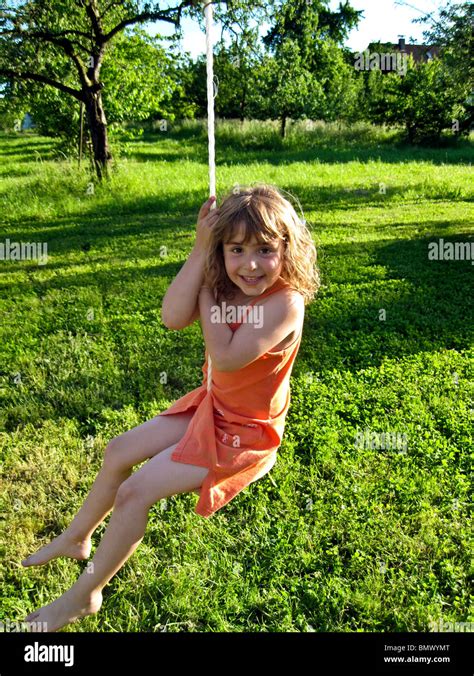 4 Años Chica Alemana En Traje Naranja Jugando En Un Columpio Al Aire Libre Con Un Pasto Verde