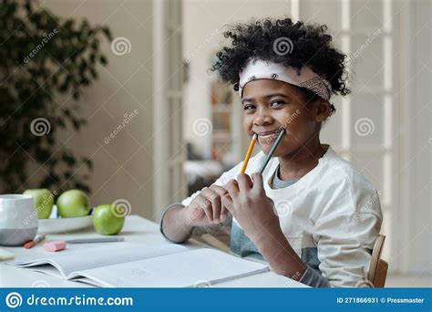 Cute Schoolboy Having Fun While Holding Two Pencils By Edges Of Mouth