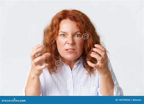 angry and hateful middle aged redhead woman looking outraged and bothered grimacing from hatred
