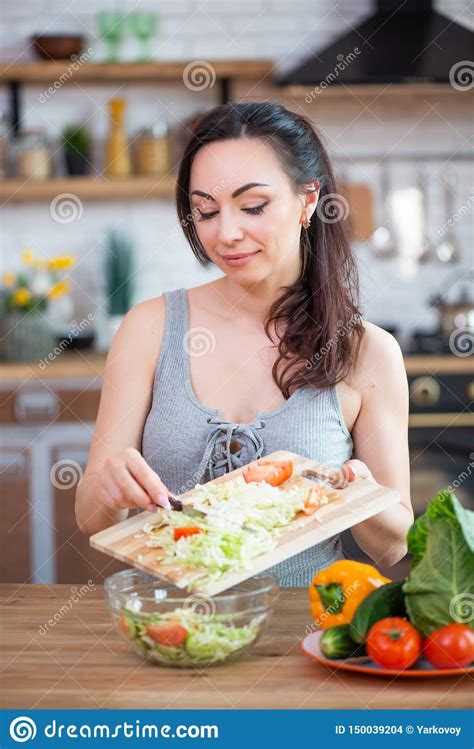 Pretty Young Woman Cutting Vegetables Salad In The Kitchen Stock Photo