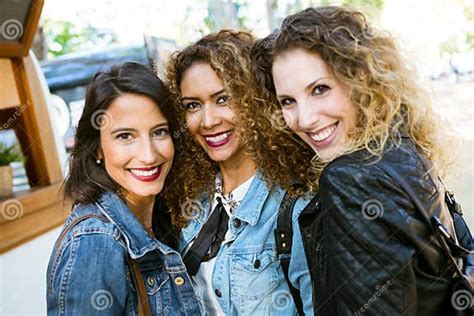 Three Beautiful Young Women Looking At Camera In The Street Stock