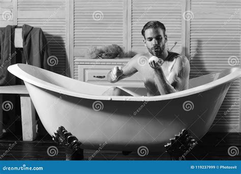 sexuality and relaxation concept macho playing with foam in bathtub guy in bathroom stock