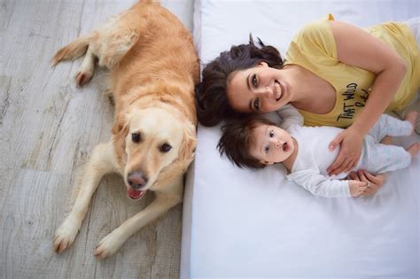 La Madre Con Su Hija Se Acuesta En La Cama Y El Perro Los Mira Foto