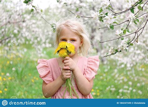 Beautiful Little Girl Smelling Flowers Outside In Under The Apple Trees