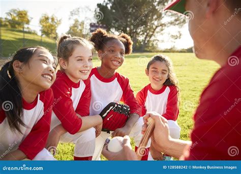 Girl Baseball Team In A Team Huddle With Coach Listening Stock Photo