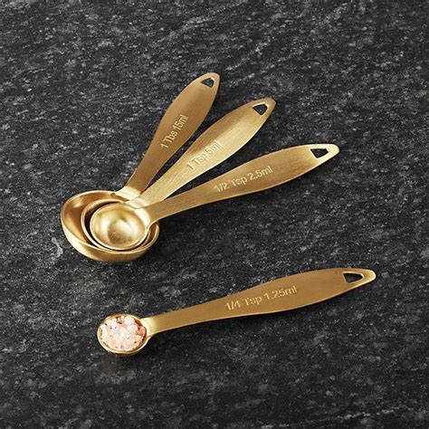 Three Gold Measuring Spoons On Top Of A Granite Countertop With The