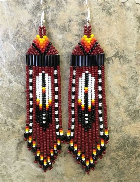 Two Pairs Of Beaded Earrings With Feathers On Them And Beads Hanging