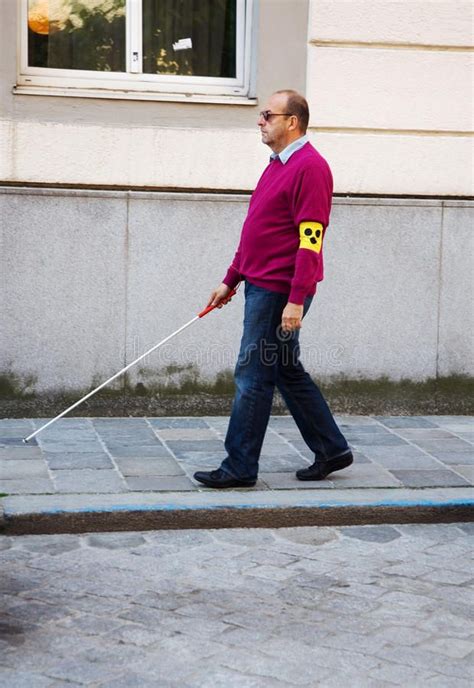 A Man Walking Down The Street With A Stick In His Hand And A Smiley