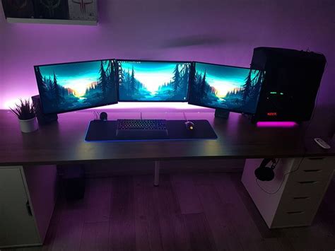 Three Computer Monitors Sitting On Top Of A Desk In Front Of A Purple