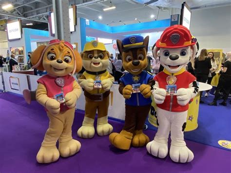 Three Mascot Dogs Standing Next To Each Other On A Purple Carpet At An