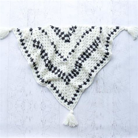 A Crocheted Triangle With Tassels Hanging From It S Sides On A White Surface