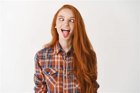 premium photo funny redhead girl showing tongue and squinting making playful faces standing