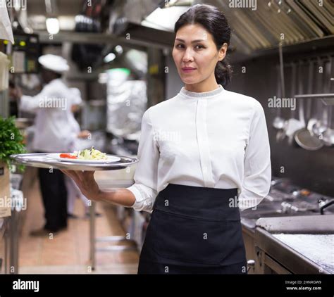 Successful Waitress Standing In Restaurant Kitchen With Ordered Meals