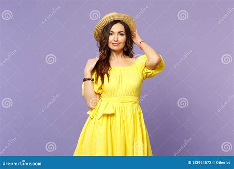 Attractive Young Woman In Yellow Dress Keeping Hand On Summer Hat