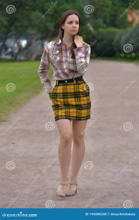 Slender Brunette Girl In A Plaid Skirt In The Summer In The Park Stock