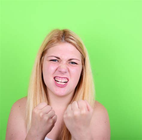 Portrait Of Angry Girl Holding Fists Against Green Background Stock