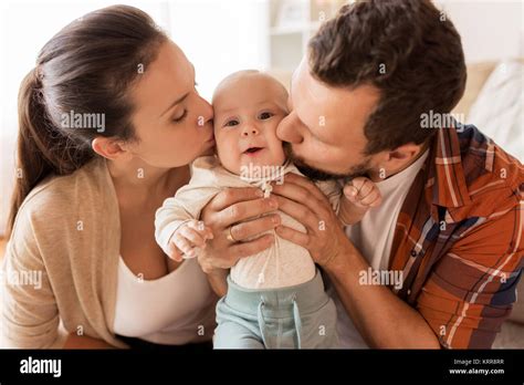 Feliz Madre Y Padre Besar A Bebé En El Hogar Fotografía De Stock Alamy