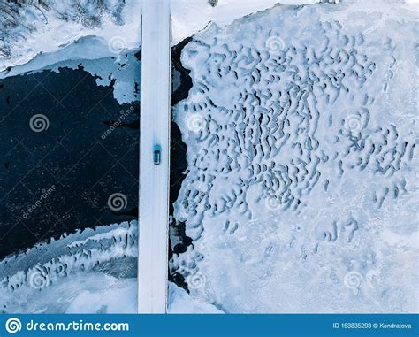 Aerial Top View Of Bridge Road Above Frozen River In Snow Winter