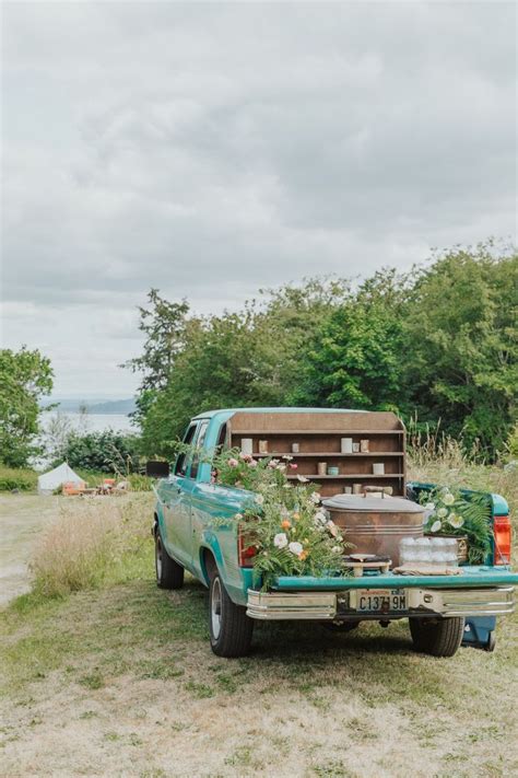 An Old Pick Up Truck With Flowers In The Back Parked Next To A Wooden Box