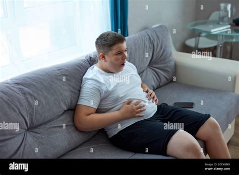 Fat Teenager Boy Has Stomach Ache After Junk Food Sit On Sofa Holding