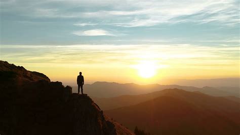 The Male Standing On The Mountain And Enjoying The Beautiful Sunset