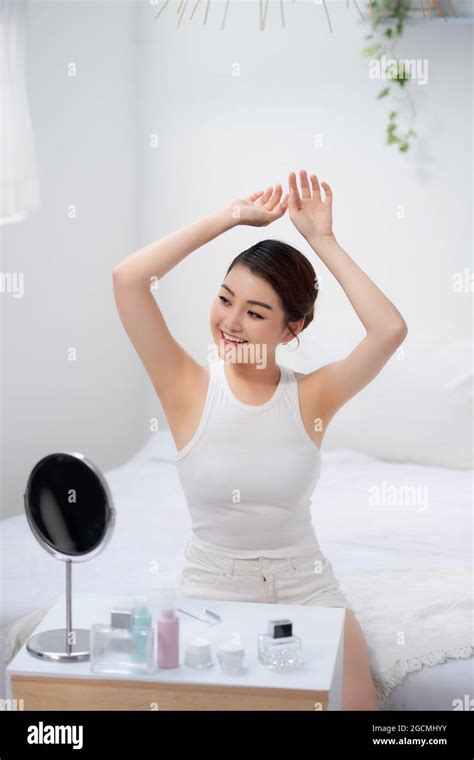 Slim Young Woman Shows Tender Smooth Armpit Skin In Bedroom Stock Photo