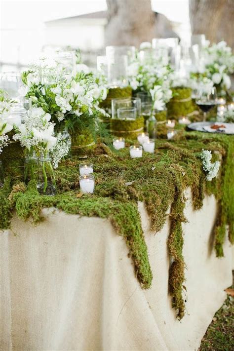 Moss Covered Tables With White Flowers And Candles