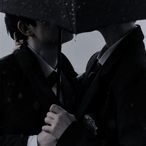 Two People Standing Under An Umbrella In The Rain With Their Heads Close To Each Other