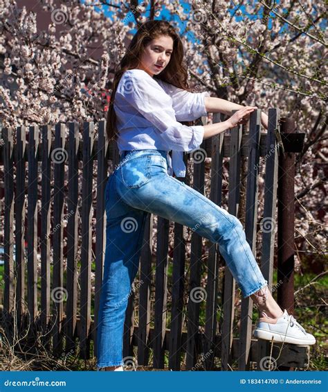 Portrait Of A Young Stylish Girl In In Blue Jeans Against The