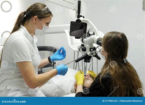 Dentist Doctor And Nurse Treat Teeth To A Patient Using A Microscope