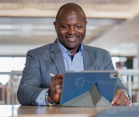 Portrait Of Happy Black Businessman In Suit Sitting At Desk In Modern