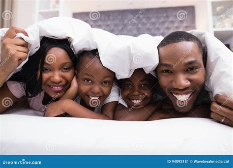 Retrato De La Familia Feliz Que Miente Junto Debajo De La Manta En Cama